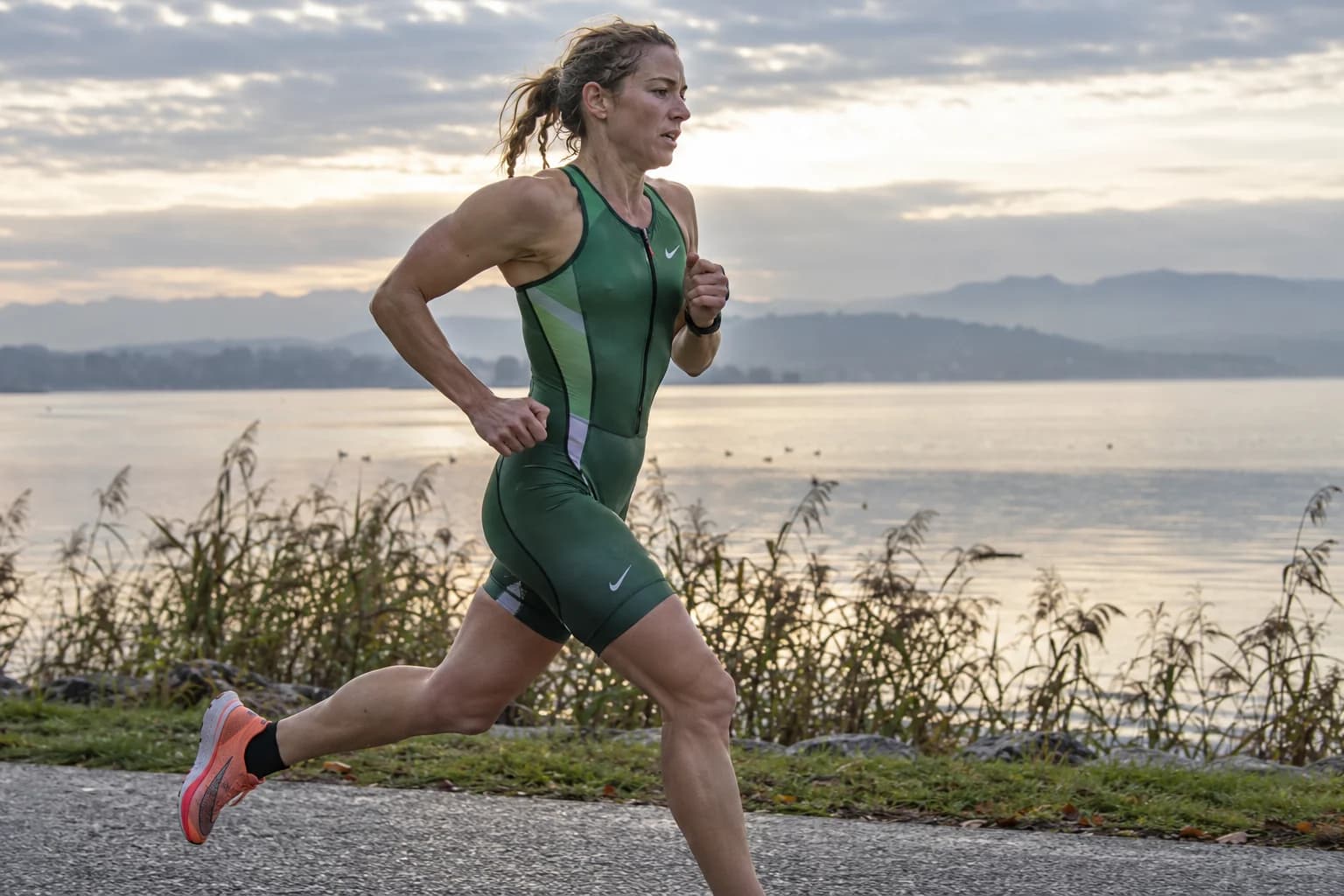 AI-gegenereerd sfeerbeeld: triatlete die over een vlak pad langs een meer rent